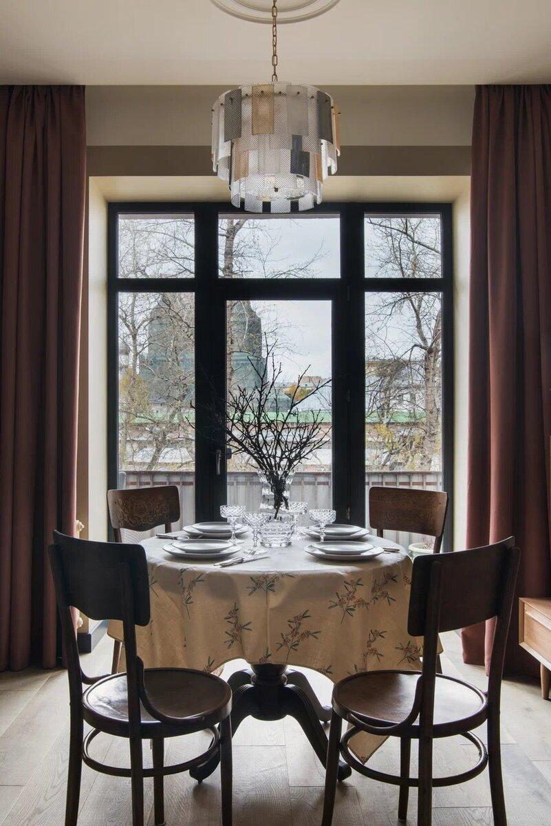 Иногда по праздникам и особо важным поводам в гостиную выносят обеденный стол из кухни (обратите внимание, как интересно сочетаются веточки в вазе с осенними деревьями за окном)